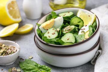 Useful spinach salad, cucumbers, eggs and seeds (pumpkin, flax and sunflower) with lemon and olive oil. Dietary food. Healthy Breakfast or dinner. Selective focus