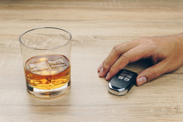 do not drink and drive concept, man with a remote car key and a glass of bourbon whiskey