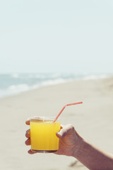 man with an orange drink on the beach
