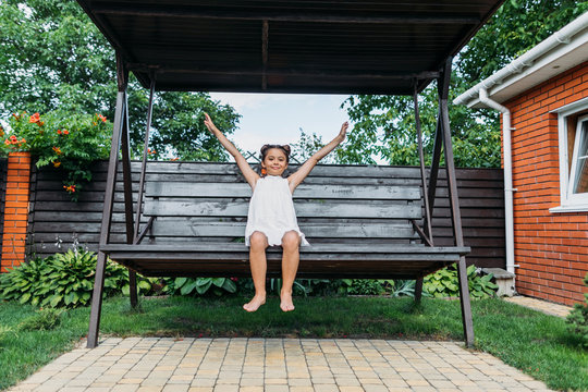 cute little kid with outstretched arms resting on wooden bench in summer day