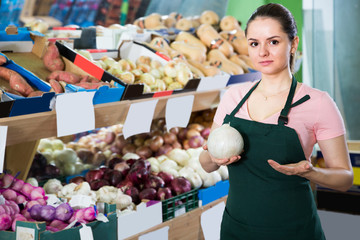 young saleswoman in store with onions in hands