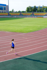 Athletic young woman in pink sneakers run on running track stadium