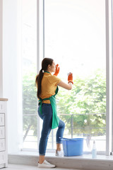 Young woman cleaning window glass at home