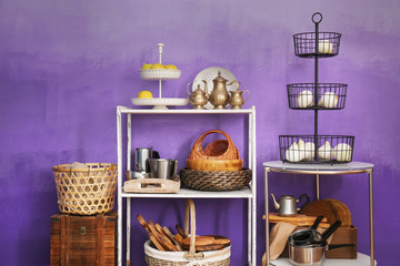 White storage stand with kitchenware near color wall