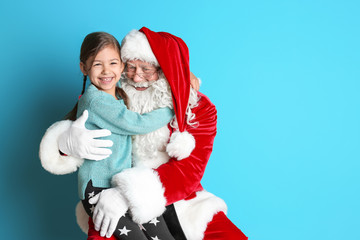 Fototapeta premium Little girl hugging authentic Santa Claus on color background
