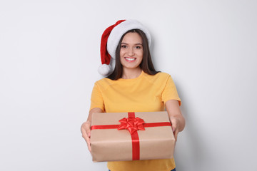 Young woman with Christmas gift on white background