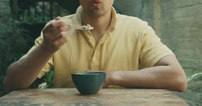 Young man eating soup outside