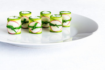 cucumber rolls with cheese and dill filling decorated with radish and green onion