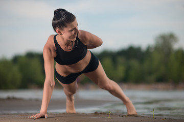 Cute woman doing push-ups on the beach against the sea