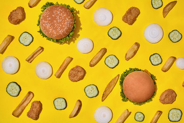Most popular fast food meal. Chicken nuggets, burgers and french fries on yellow background top view