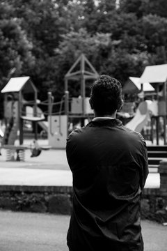 Worried man looking to a empty city playground. Converted to black and white, grain added.