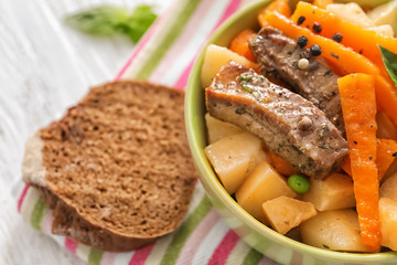 Bowl with tasty meat and potatoes on table