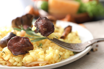 Plate with tasty risotto and mushrooms on table, closeup