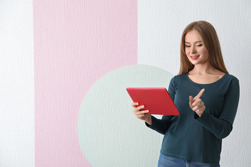 Young woman with tablet on color background