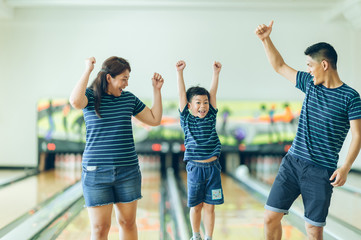 Obraz premium Success! Family and young boy in bowling alley