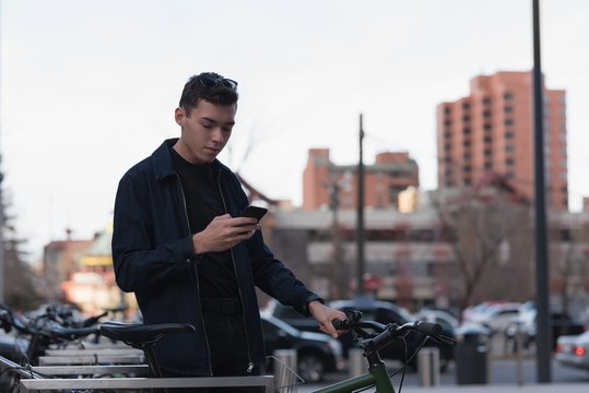 Man standing next to his bike and using mobile phone