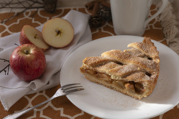 A apple pie slice with natural apples on the side