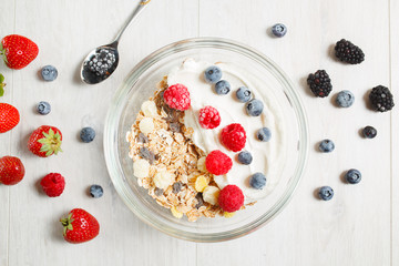 Granola with yogurt in glass and berries, strawberries, blackberries, blueberries, raspberries.