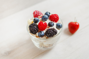 Granola with yogurt in glass and berries, strawberries, blackberries, blueberries, raspberries.