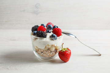 Granola with yogurt in glass and berries, strawberries, blackberries, blueberries, raspberries.