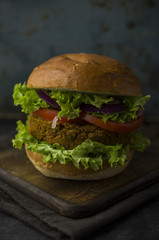 Vegan burger with vegetables on cutting board