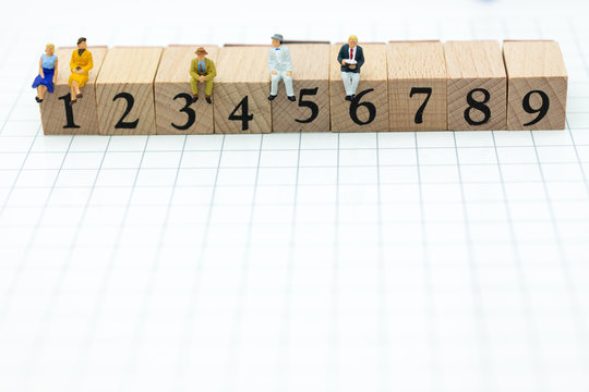 Miniature people : Businessman sitting on wooden blocks with sequential numbers. Image use for business concept.