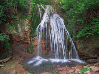 Fototapeta na wymiar Big waterfall at the green forest in europe