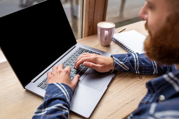 Cropped image of young man chatting via net-book during work bre
