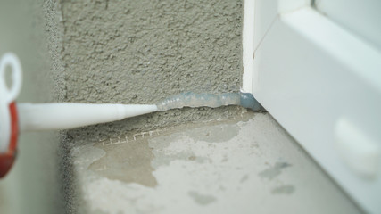 Closeup construction work applying silicone sealing with caulking gun for moisture protection....