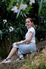 Woman sitting on stairs in tropical greenery with flowers