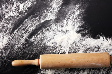 Baking background with the rolling pin with flour. On the dark table. Free space for text