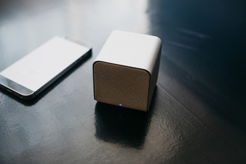 Wireless speakers and a cell phone next to them on a dark background. Modern technology for...