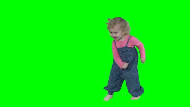 Playful active toddler girl jumping and moving isolated on green background