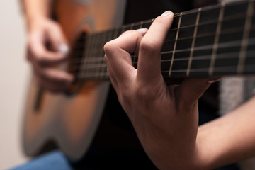 Mädchen spielt Gitarre, linke Hand scharf, rechte Hand unscharf