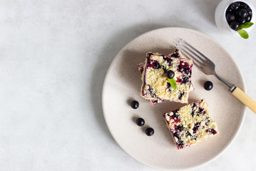 Black currant cake. Cheesecake bars with lemon, black currant and streusel on a plate.
