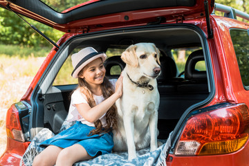 adorable kid hugging dog on car trunk