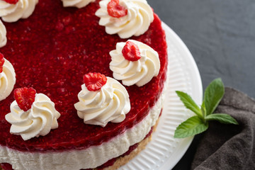 Raspberry cheesecake with whipped cream and fresh raspberries on a white plate.Copy space.