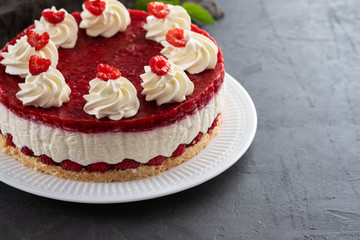 Raspberry cheesecake with whipped cream and fresh raspberries on a white plate.Copy space.
