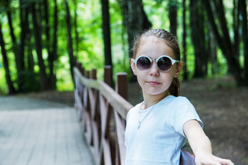 portrait of cute smiling girl in the forest in sunglasses