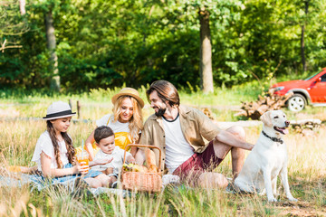 happy parents and children spending time at picnic with dog