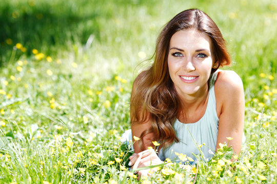 Young Woman In Blue Dress Lying On Grass