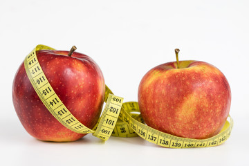 Red apples and a measure of tailor on a white table. Ripe fruits and a tailor's centimeter.