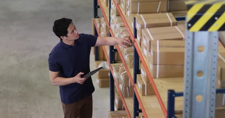 Overhead shot of male working in distribution warehouse with digital tablet