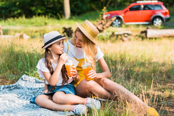mother and daughter drinking juice at picnic