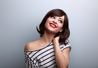 Happy thinking romantic makeup young woman with short hairstyle looking up on empty blue copy space.