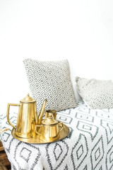 Modern minimal home interior design. Pillows, golden teapot, tray, Scandinavian blanket.
