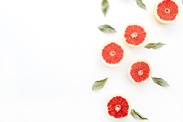 Sliced grapefruits and green leaves on white background.