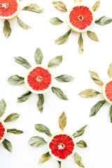 Sun symbol pattern made of sliced grapefruit and leaves. Flat lay, top view summer creative concept.