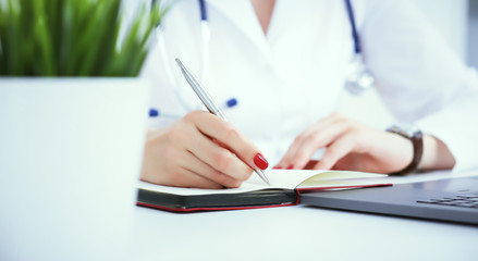Female medicine doctor hand holding silver pen writing something on clipboard and working laptop closeup. Physician ready to examine patient and help
