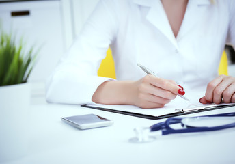 Female medicine doctor hand holding silver pen writing something on clipboard and working laptop closeup. Physician ready to examine patient and help